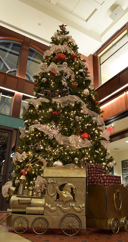 An image of a large train model placed at the base of a Christmas tree