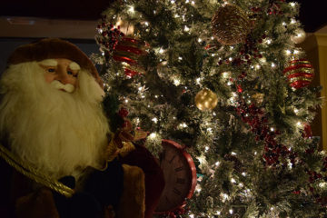 An image of a Christmas tree decorated with ornaments and lights and a stuffed Santa Clause