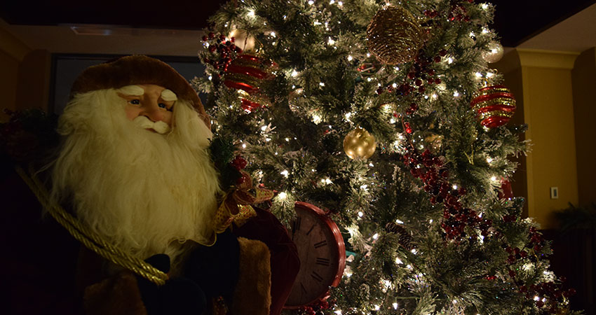 An image of a Christmas tree decorated with ornaments and lights and a stuffed Santa Clause
