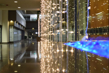 An image of holiday lights hanging inside of a corporate building’s atrium